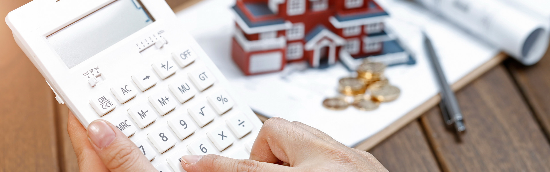 a-female-hand-operating-a-calculator-in-front-of-a-villa-house-model.jpg